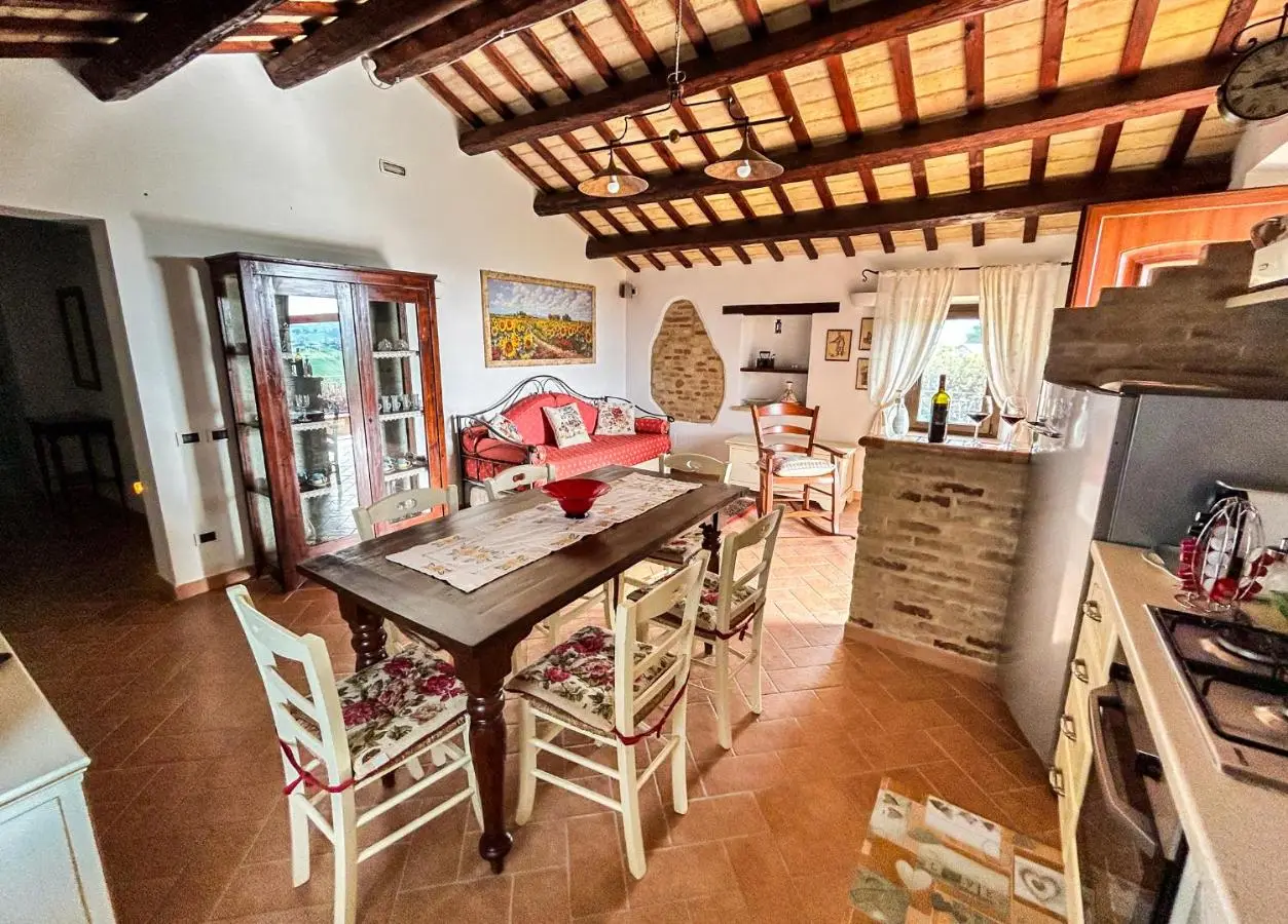 Soggiorno con travi in legno, tavolo da pranzo e cucina