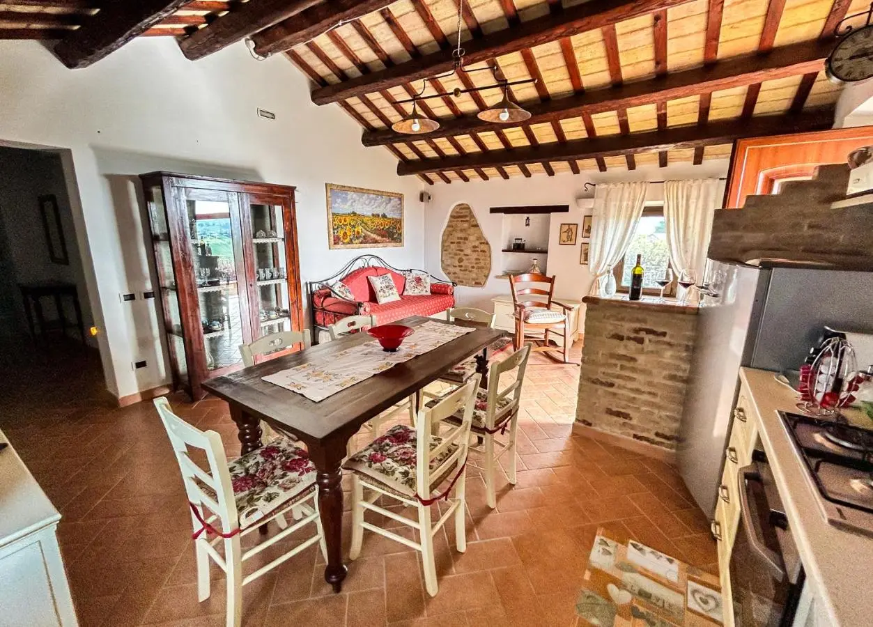 Soggiorno con travi in legno, tavolo da pranzo e cucina