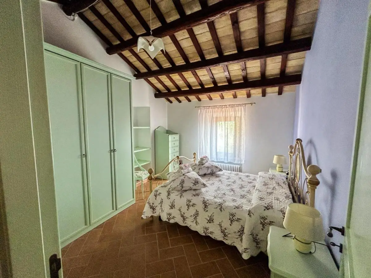 Camera matrimoniale con soffitto a travi e armadio verde