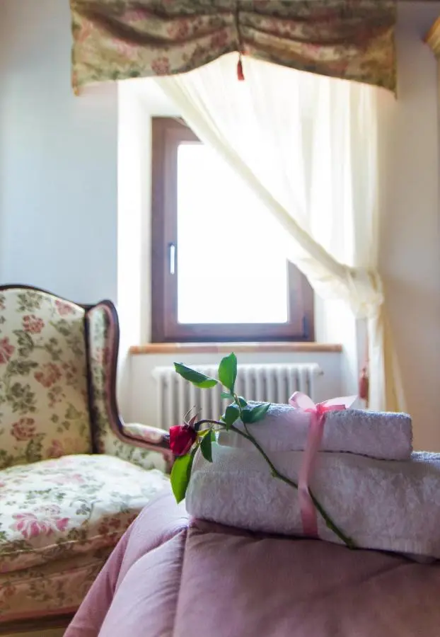 Asciugamani con rosa su letto e poltrona floreale