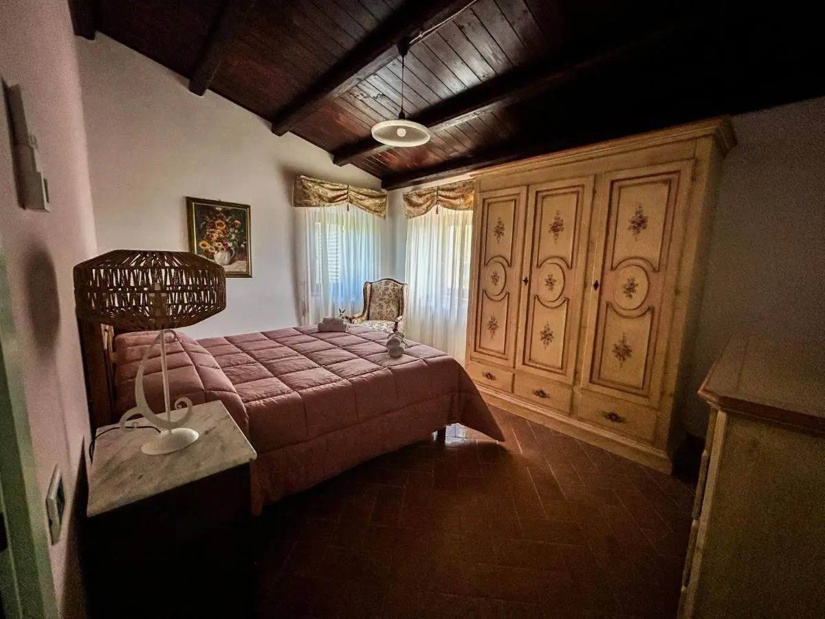 Camera con armadio decorato, travi in legno e poltrona