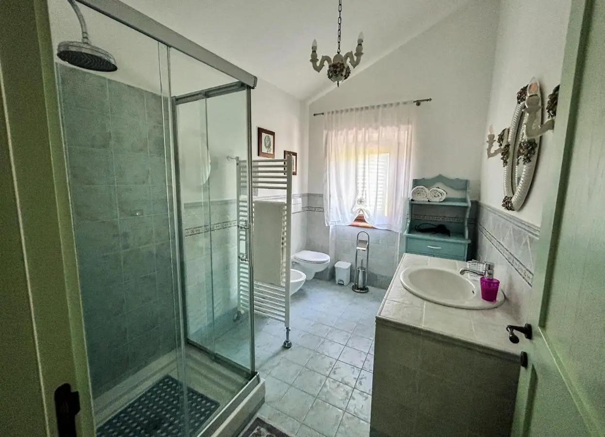 Bagno con doccia in vetro, lavabo e mobile azzurro