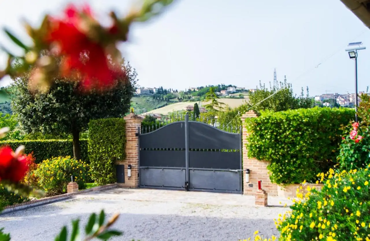 Cancello d'ingresso con siepi, fiori e colline