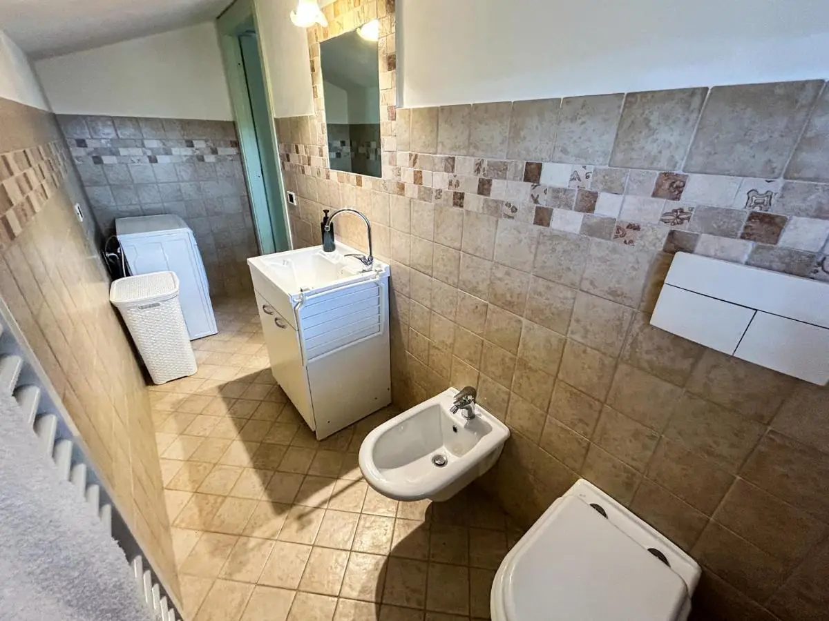 Bagno piastrellato con lavabo, bidet e lavatrice